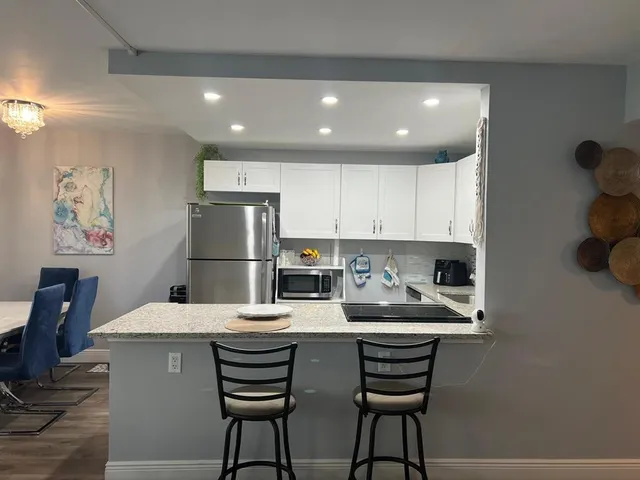 a kitchen with a dining table chairs and refrigerator