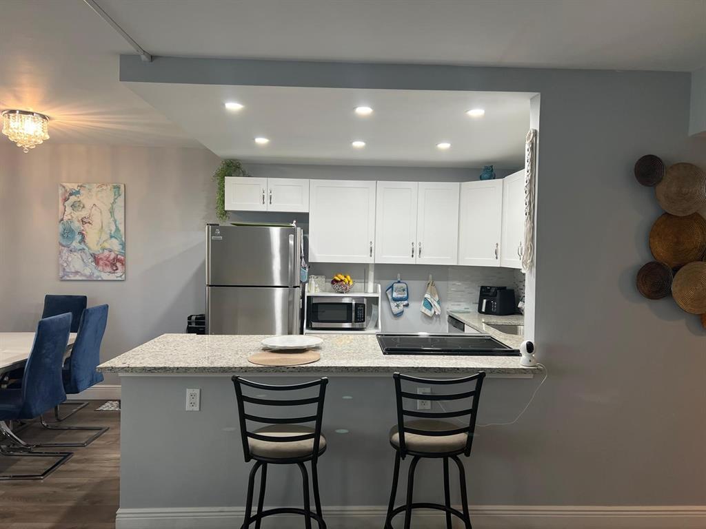 418 Durham, Unit 418 Deerfield Beach, FL 33442 - Photo 26 of 47 a kitchen with a dining table chairs and refrigerator