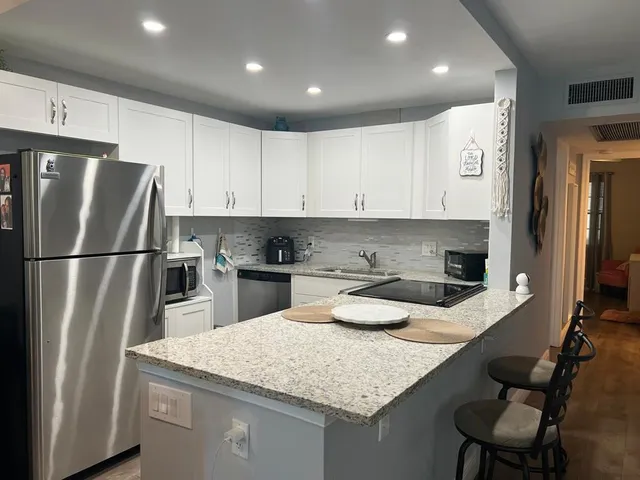 a kitchen with stainless steel appliances granite countertop a sink refrigerator and cabinets