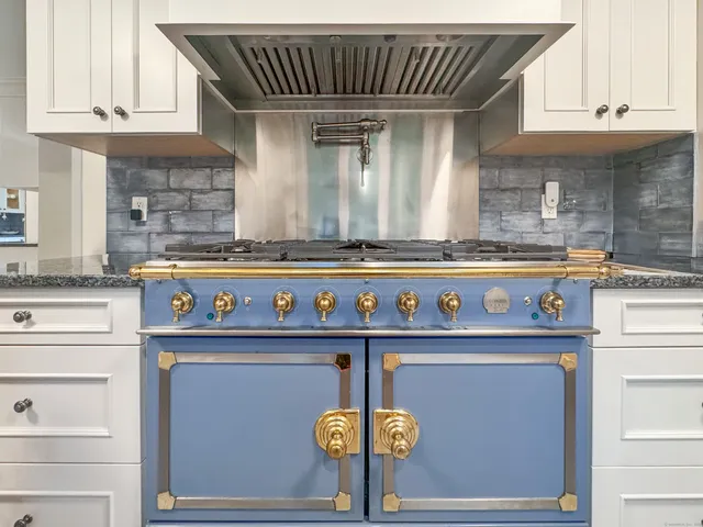 a kitchen with a stove and a white wooden cabinets