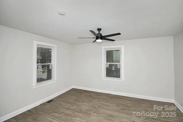 a view of a big room with wooden floor and windows