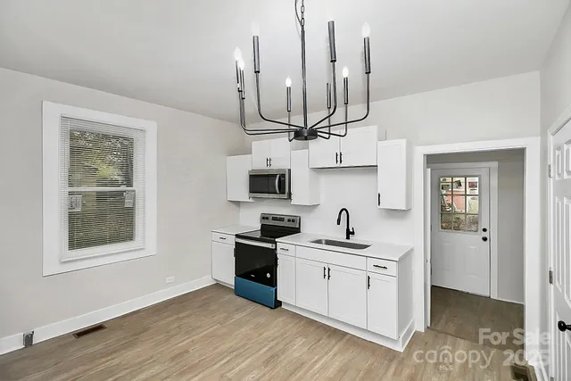a kitchen with stainless steel appliances kitchen island a sink cabinets and wooden floor