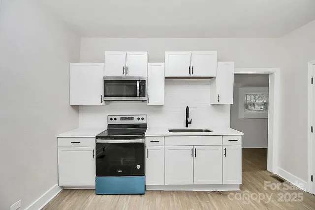 a kitchen with white cabinets and stainless steel appliances