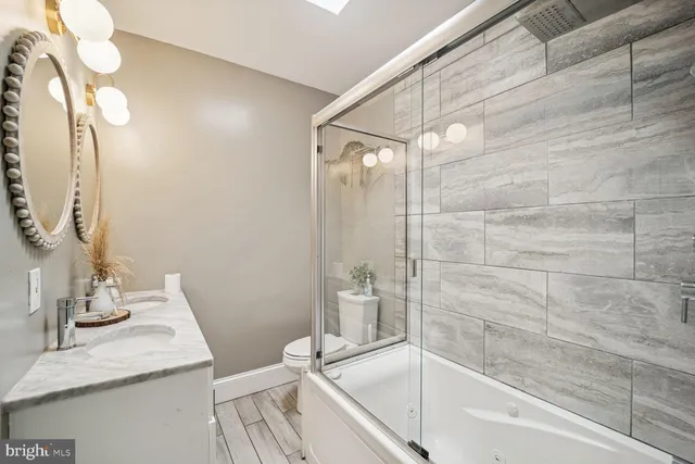 a bathroom with a granite countertop sink a toilet and shower