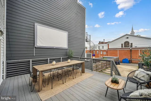 a roof deck with a dining table and chairs with wooden floor