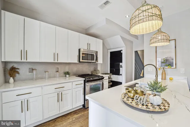 a kitchen with stainless steel appliances granite countertop a stove a sink dishwasher and white cabinets with wooden floor