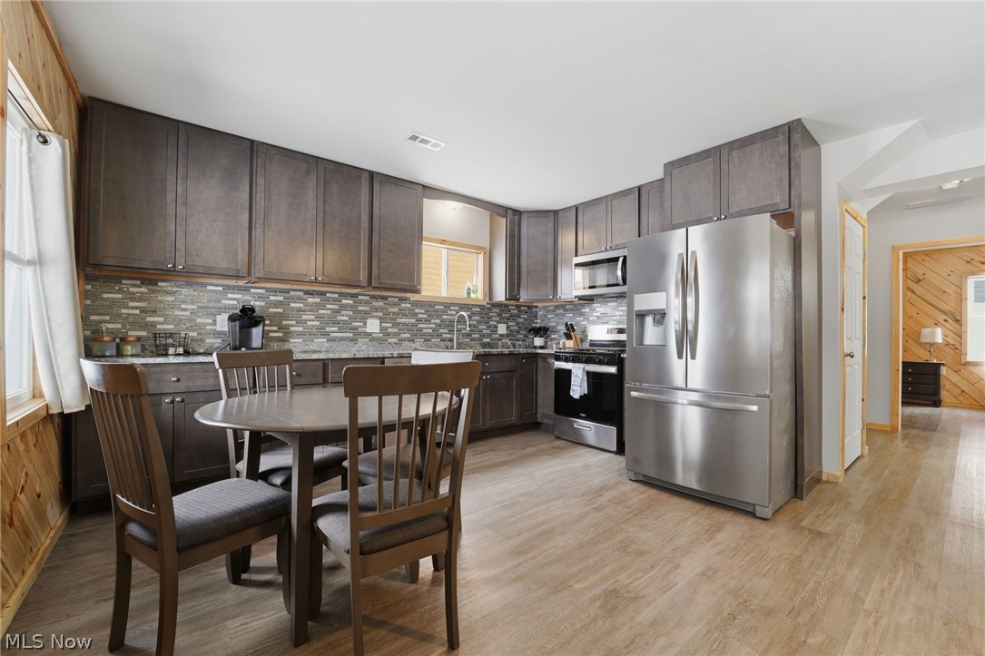 5919 Lake Road West, Unit 33 Ashtabula, OH 44004 - Photo 6 of 22 Kitchen featuring dark wood finish cabinets, stainless steel appliances, wooden walls, light wood-style floors, and decorative backsplash