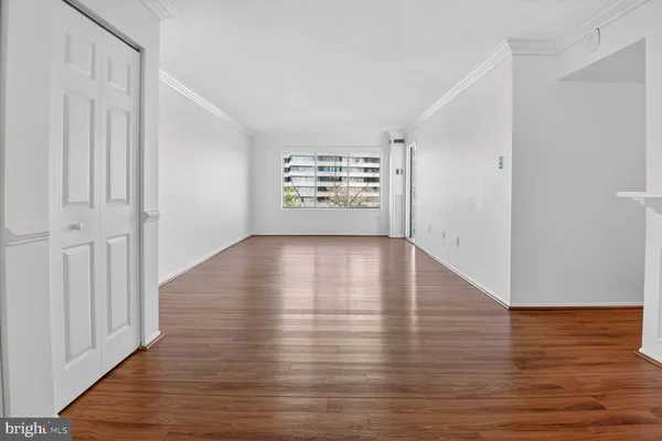 a view of an empty room with wooden floor and a window