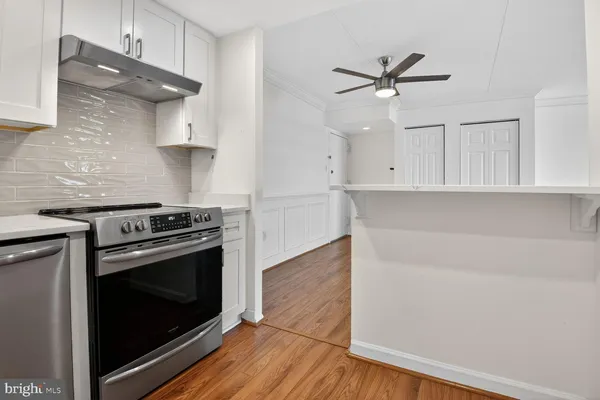 a kitchen with stainless steel appliances white cabinets and a wooden floor