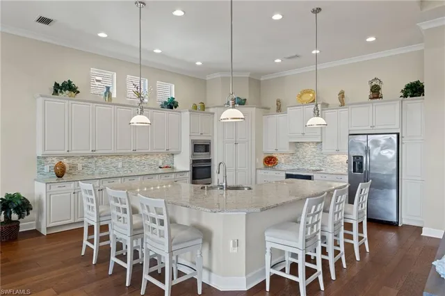 a kitchen with stainless steel appliances kitchen island granite countertop a table chairs and a refrigerator