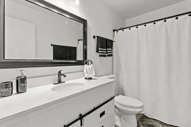 a bathroom with a sink a toilet a mirror and shower curtain