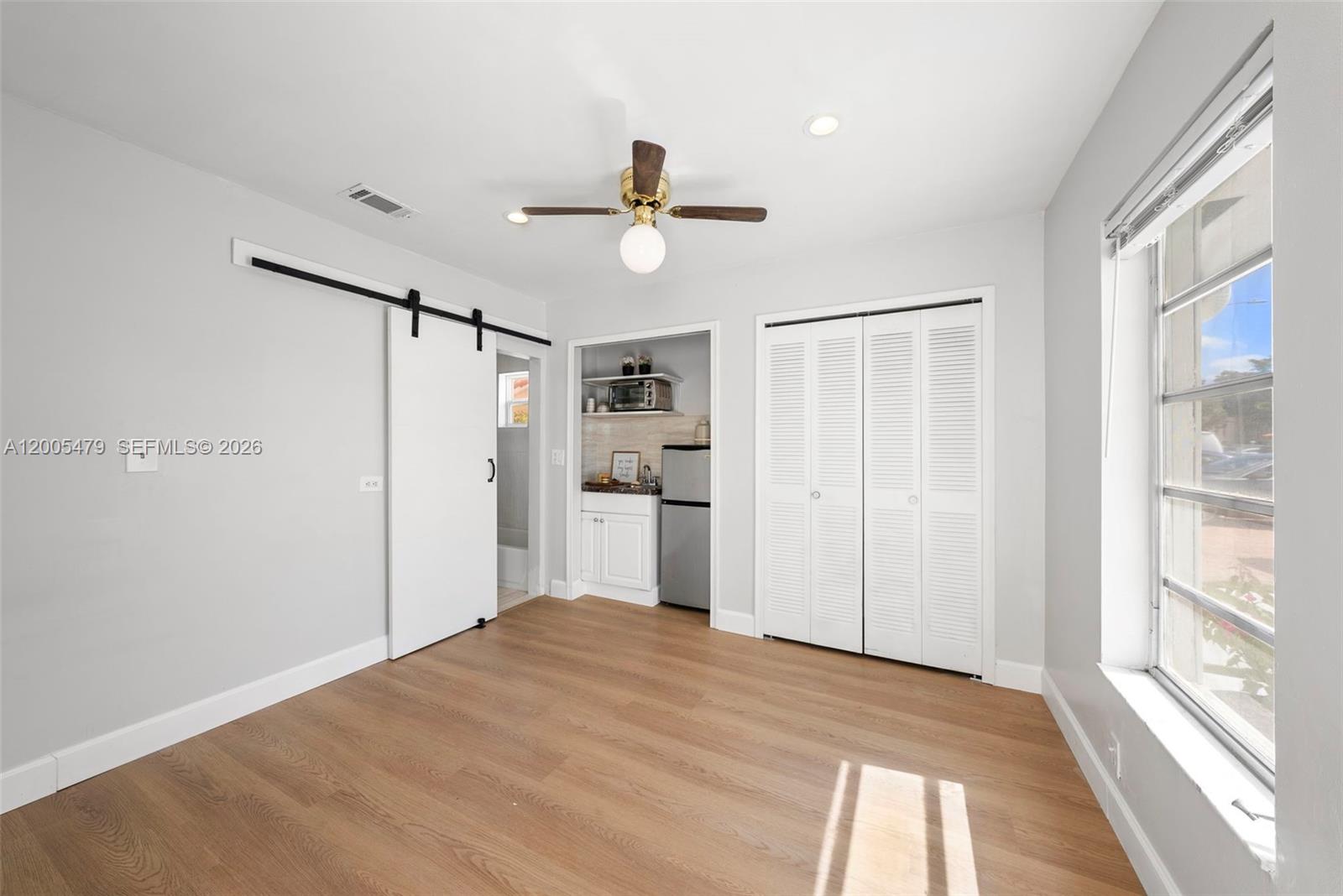 31 Northwest 108th Court, Unit E Miami, FL 33172 - Photo 2 of 5 a view of empty room with wooden floor and window