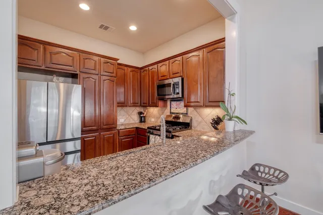 a kitchen with granite countertop wooden cabinets a refrigerator and a sink