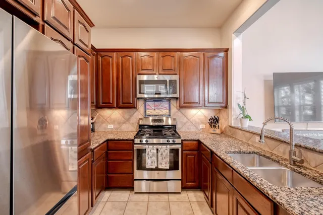 a kitchen with granite countertop a sink stove and refrigerator