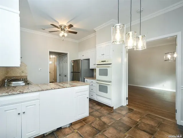 a room with kitchen island granite countertop appliances cabinets and a counter top space