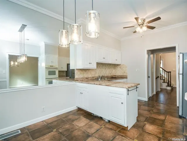 a kitchen with granite countertop a stove a sink and a chandelier