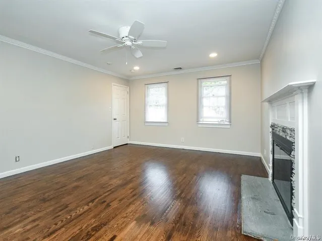 an empty room with wooden floor fireplace and windows