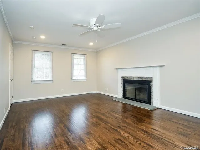 a view of an empty room with wooden floor fireplace and a window
