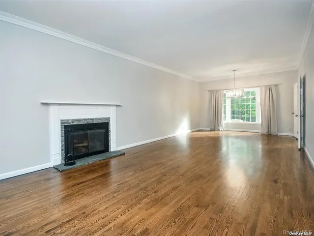 an empty room with wooden floor fireplace and windows