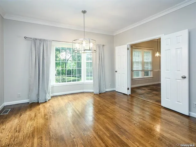 a view of an empty room with glass door and wooden floor