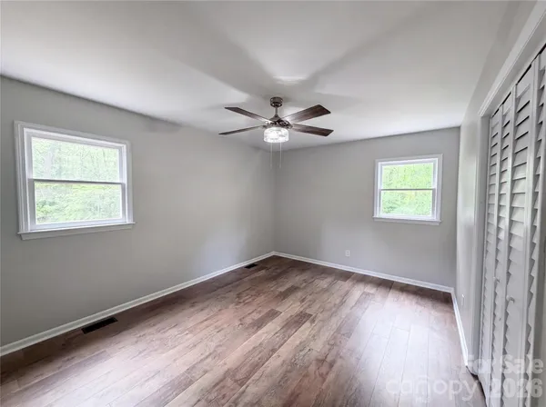 a view of an empty room with wooden floor and a window