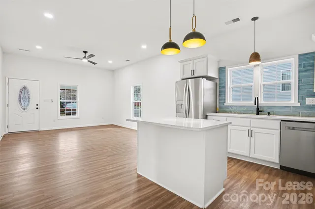 a kitchen with stainless steel appliances granite countertop a sink a stove and a wooden floors