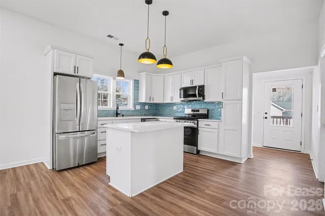 a kitchen with stainless steel appliances granite countertop a refrigerator a stove microwave and a wooden floors