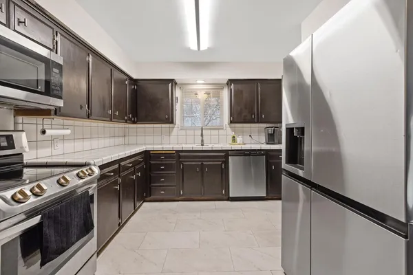 a kitchen with stainless steel appliances granite countertop a stove a sink and a microwave