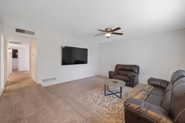 a living room with furniture a ceiling fan and a rug