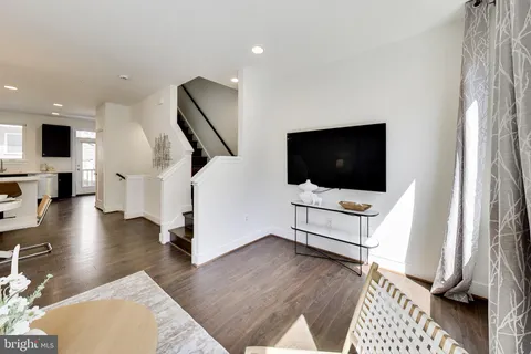 a kitchen with stainless steel appliances kitchen island granite countertop a sink a stove a dining table and chairs with wooden floor