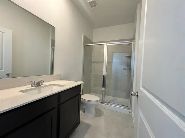 a bathroom with a shower sink vanity mirror and toilet