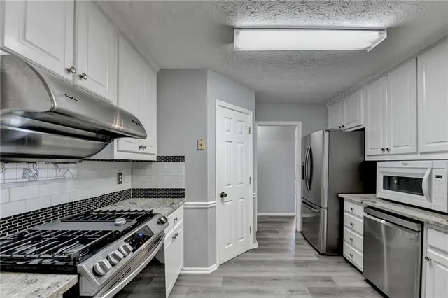 a kitchen with granite countertop white cabinets and stainless steel appliances