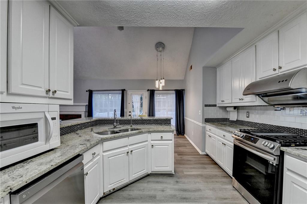 235 Ruby Forest Parkway Suwanee, GA 30024 - Photo 30 of 59 a kitchen with granite countertop wooden cabinets stove top oven and sink