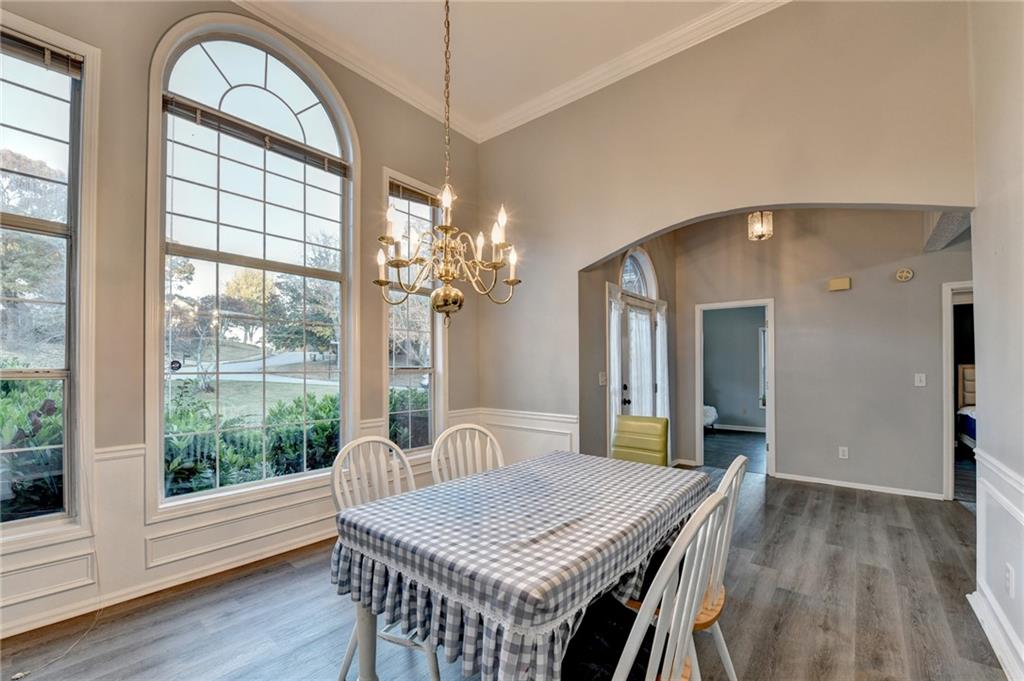 235 Ruby Forest Parkway Suwanee, GA 30024 - Photo 8 of 59 a dining room with wooden floor a chandelier a wooden table and chairs