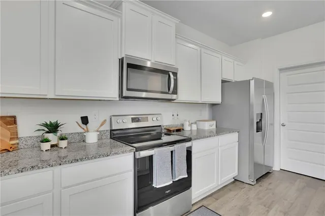 a kitchen with stainless steel appliances granite countertop white cabinets sink and stove