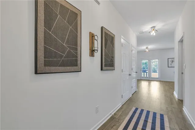 a view of a hallway with wooden floor and a bathroom