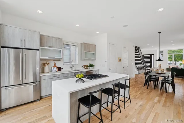 a kitchen with stainless steel appliances a dining table chairs stove and refrigerator
