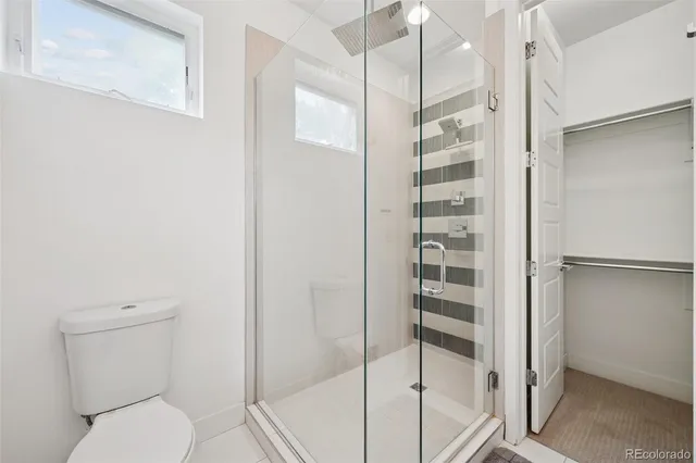 a bathroom with a toilet and a glass door shower