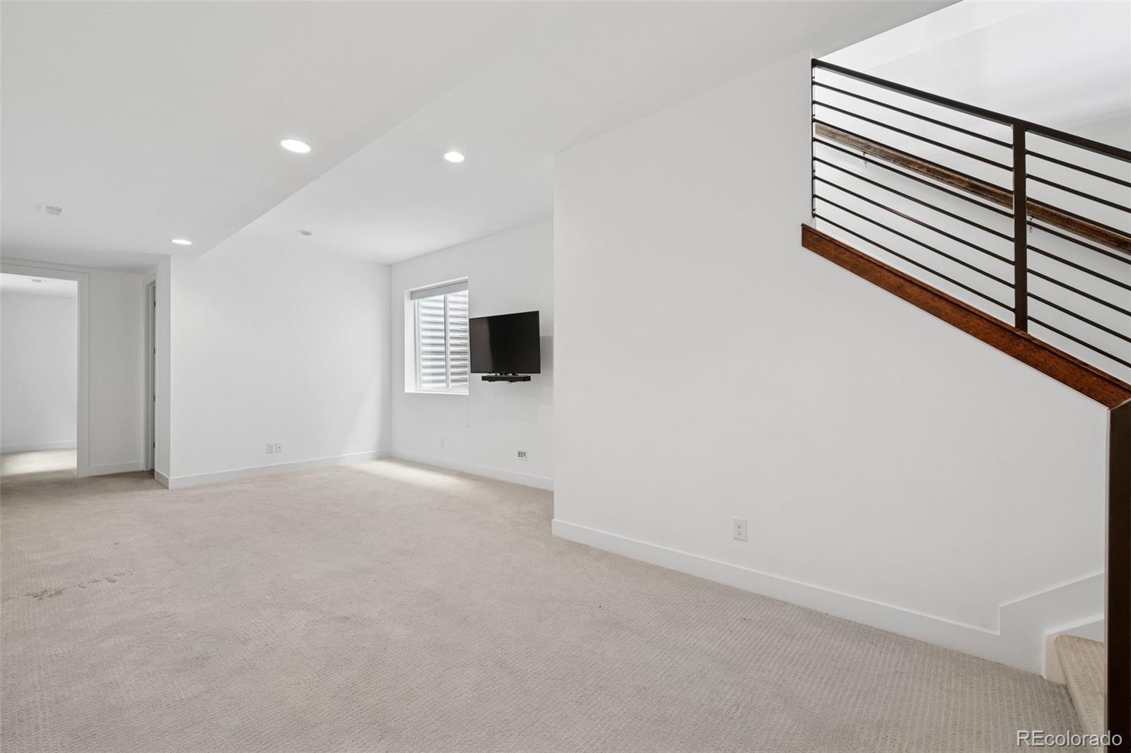 1833 East Jewell Avenue Denver, CO 80210 - Photo 31 of 41 a view of an empty room with wooden floor and a flat screen tv