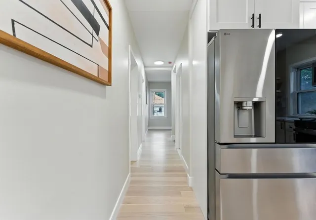 a view of a refrigerator in kitchen and an empty room