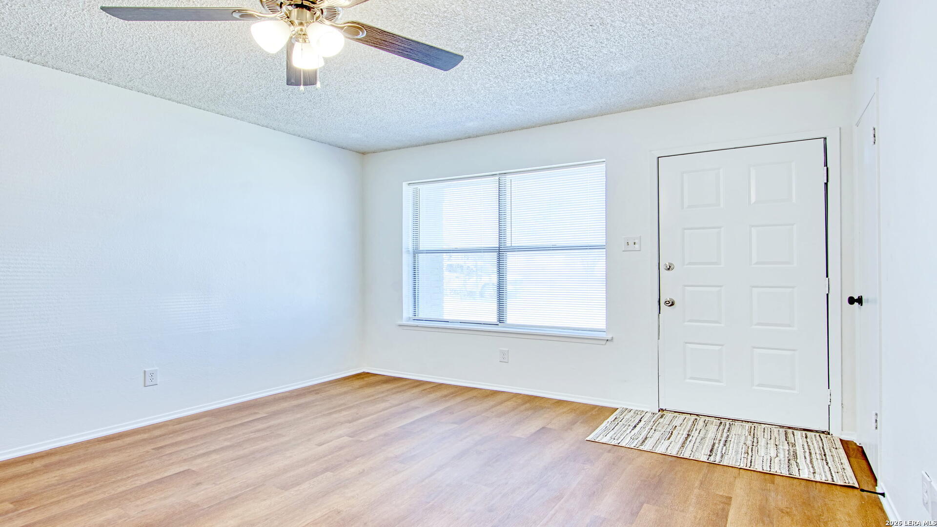 406 Pine Street Kenedy, TX 78119 - Photo 3 of 31 an empty room with wooden floor fan and windows