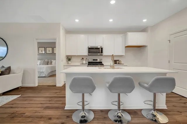 a kitchen with granite countertop a counter space chairs cabinets and stainless steel appliances