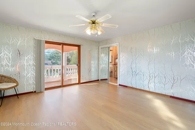 an empty room with wooden floor fan and windows
