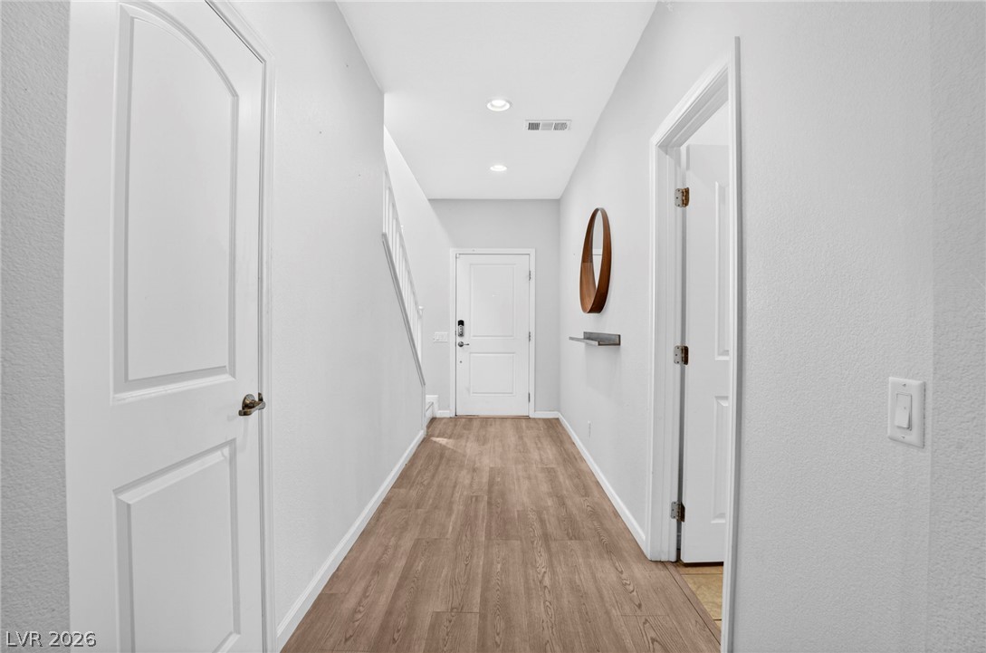6281 Angora Peak Lane Las Vegas, NV 89115 - Photo 5 of 34 A well-lit entry hall with wood-look flooring leads to a staircase and several white interior doors.