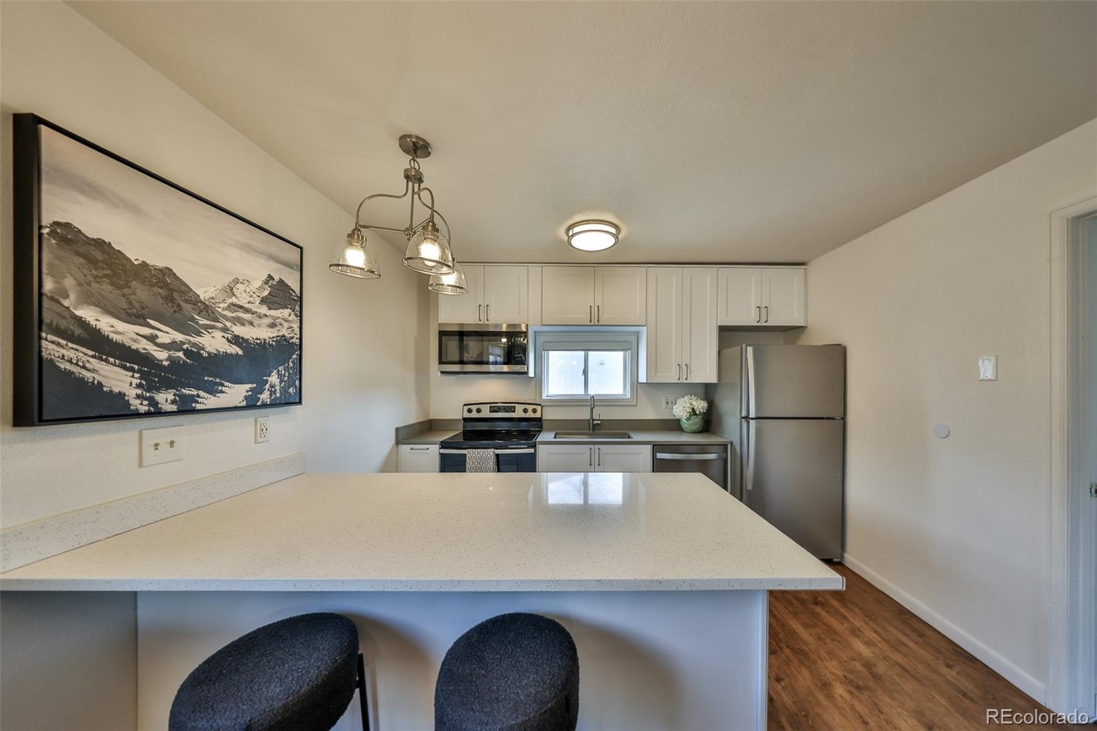 233 Fraser Avenue, Unit R1 Fraser, CO 80442 - Photo 4 of 23 a kitchen with stainless steel appliances a stove a refrigerator a sink and white cabinets with wooden floor