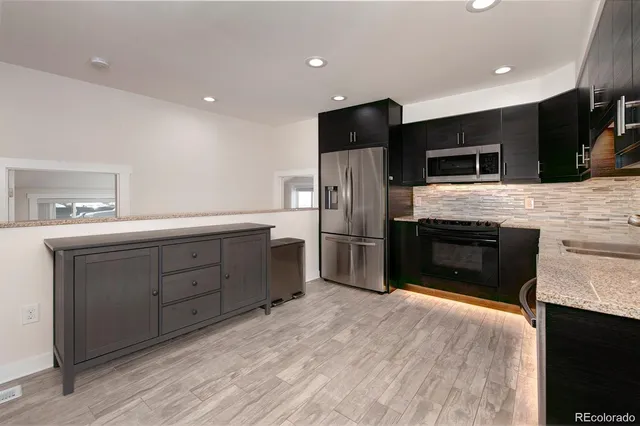 a kitchen with stainless steel appliances kitchen island granite countertop a stove a sink and a refrigerator
