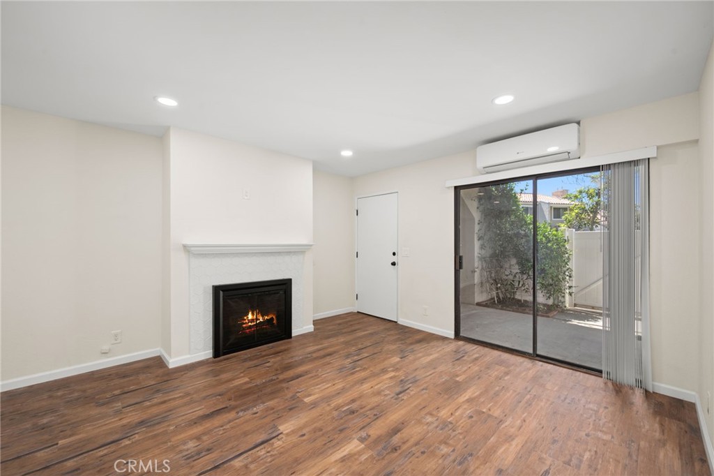 6911 Quail Place, Unit C Carlsbad, CA 92009 - Photo 3 of 18 an empty room with wooden floor fireplace and windows