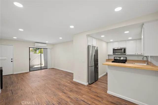 a view of kitchen with stainless steel appliances granite countertop a refrigerator and a stove top oven