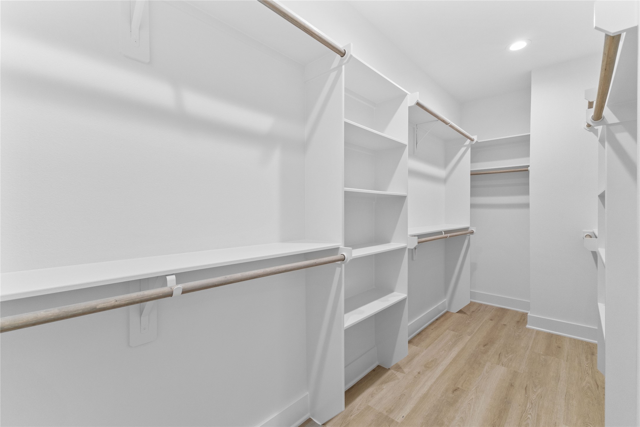 3426 Bolin Road Houston, TX 77092 - Photo 21 of 34 Primary bedroom walk-in closet.
This is a spacious, well-lit walk-in closet featuring ample shelving, hanging rods, and a wooden floor, ideal for organized storage and wardrobe management.