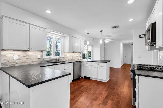 a kitchen with stainless steel appliances white cabinets and a stove top oven